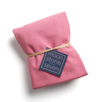 Mauve hair plop towel folded with MoonstoneSeven navy product tag and tied with twine