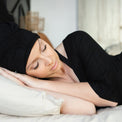 Model sleeping while wearing MoonstoneSeven Satin Sleeper to protect curls overnight